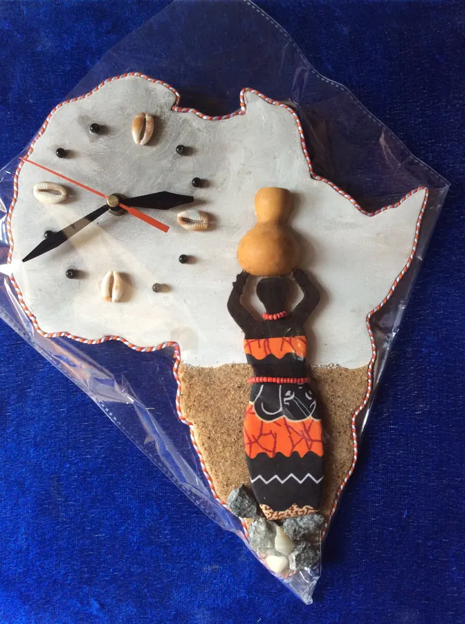Horloge murale en forme d’Afrique ornée de cauris, d’une calebasse et d’une silhouette en tissu wax